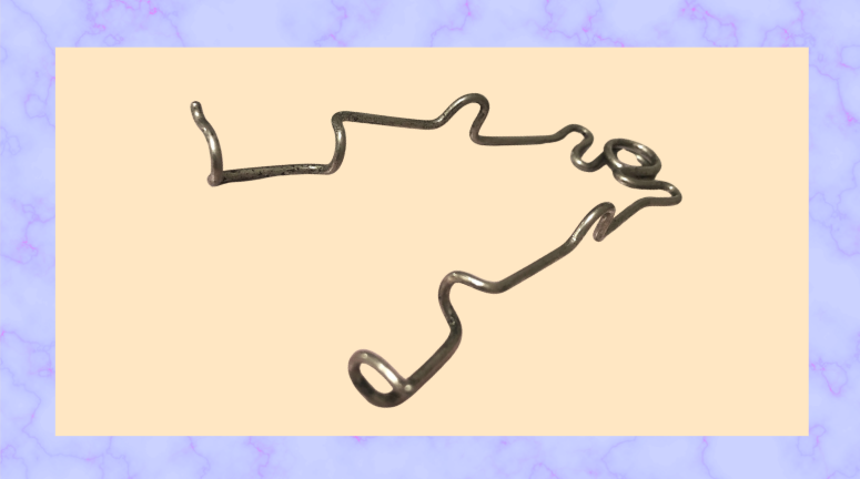 A grey metal eye speculum; it is a thin rod of metal twisted to form two bends at the ends to hold open eyelids, and it hinges on itself with a coiled circle at the other end.