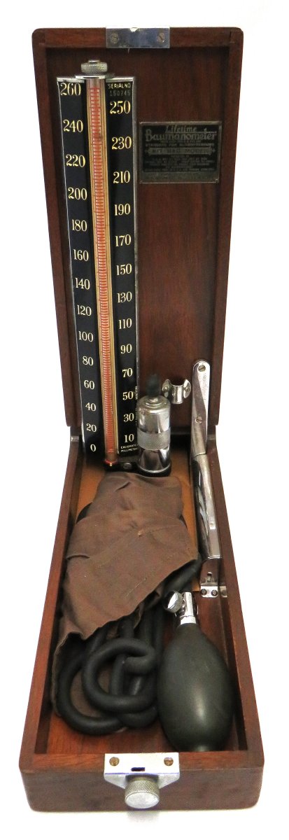 Sphygmomanometer in wooden case that opens to reveal the meter inside the lid and the bulb and tubing in the box.