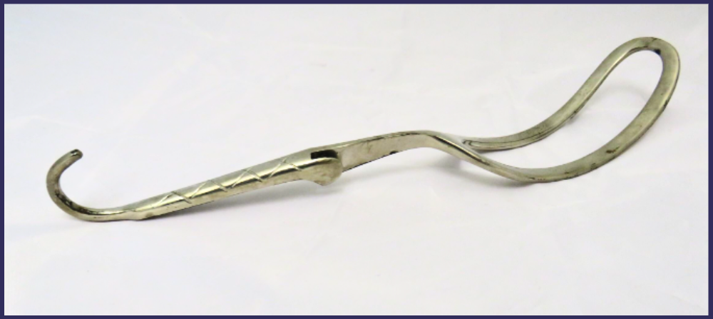 Grey metal obstetrical forcep with a curved handle and fenestrated end.